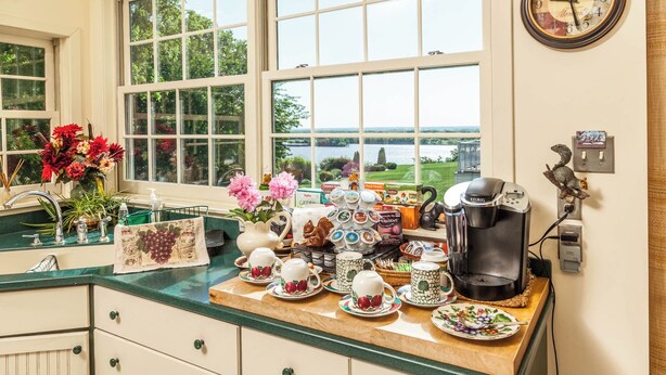 A kitchen with a view of a lake, a coffee maker, and various kitchen items on the counter.