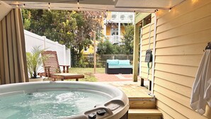 A hot tub in a covered outdoor area with a wooden deck, a lounge chair, and a small table. - Short walk to ocean and sound! NEW HOT TUB, FREE use of golf cart! Several decks (Emerald Isle)