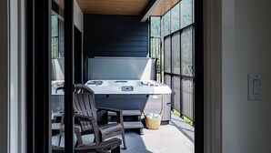 A hot tub on a balcony with a chair and a basket.