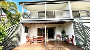 A two-story building with a balcony, outdoor seating area, and a view of the surrounding greenery.