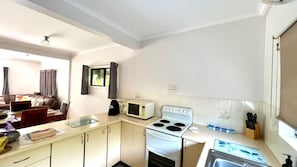 A compact kitchen with a stove, microwave, and a small sink.