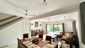 A spacious living area with a dining table, sofas, and a TV.