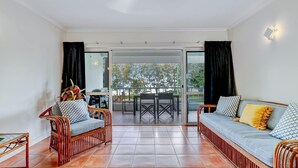 Una habitación con sofá, sillas, una mesa de comedor y vistas al exterior a través de un ventanal.