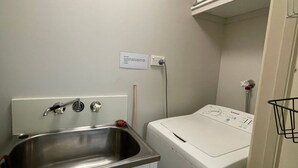 A laundry area with a washing machine, a sink, and a sign above the machine. - Liana 4 Beach Lovers All at your finger tips (Mission Beach)