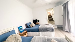 Un dormitorio moderno con una cama, una mesita de noche con televisor y una escalera que conduce a otra habitación.
