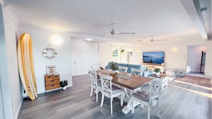 Una sala moderna con comedor, una tabla de surf y un televisor.