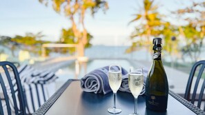 A table with a bottle and two glasses of champagne, set against a view of the sea. - Bella Luna Beach Front Full house (South Mission Beach)
