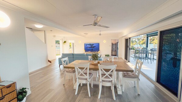 A spacious living area with a dining table, chairs, a sofa, and a television.