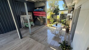 A patio with a table and chairs, a bicycle, and a small garden area. - Bella Luna Beach Front Full house (South Mission Beach)