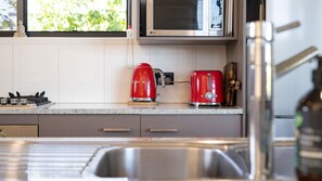 A kitchen with a stainless steel sink, a red coffee maker, and a toaster.