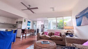 A spacious living area with a kitchen, a dining table, and a sofa. - Beaches Apt 2 Beachfront (Wongaling Beach)