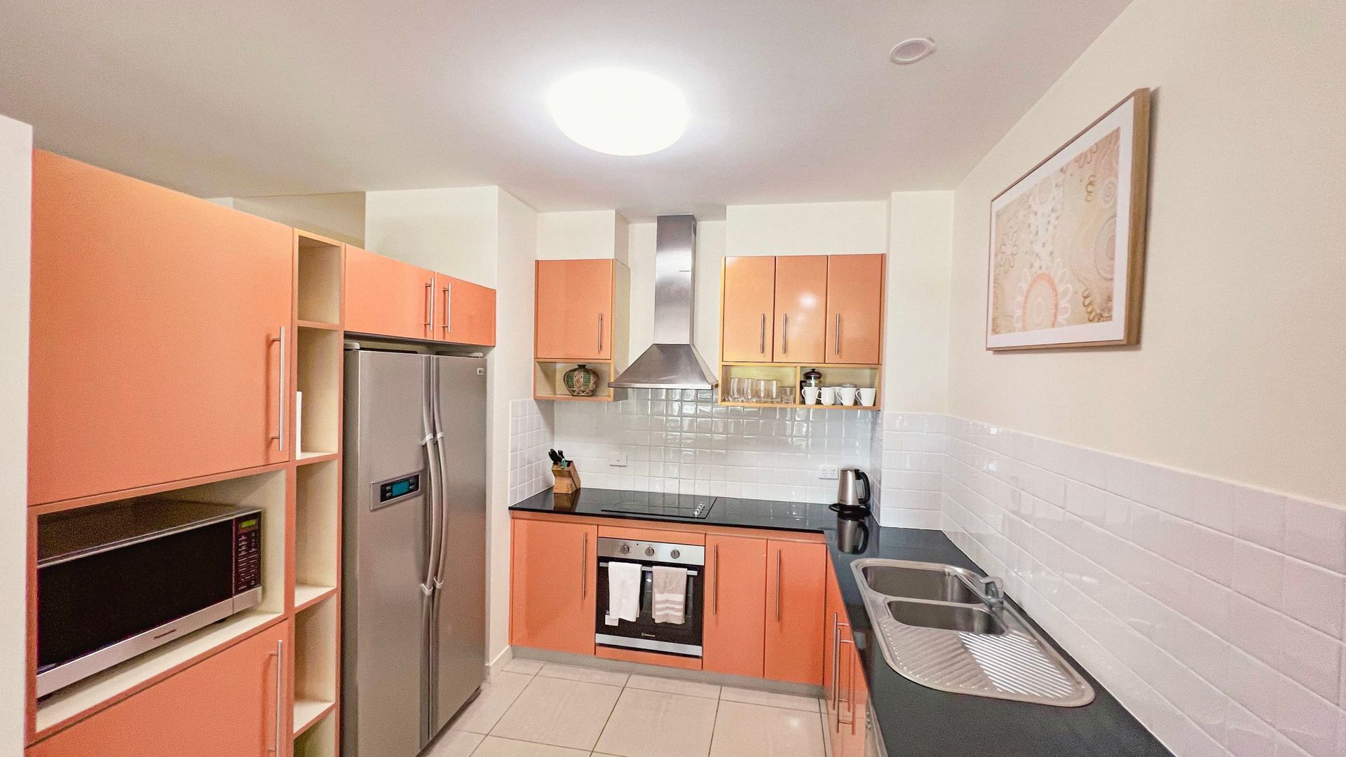 A compact kitchen with a refrigerator, oven, microwave, and sink.