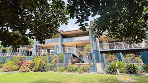 A multi-story building with balconies, surrounded by lush greenery and a well-maintained lawn.