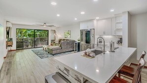 A modern kitchen with white cabinets, a large island, and a built-in oven. - South Kauai Tranquil Retreat w/ AC in Poipu (Koloa)
