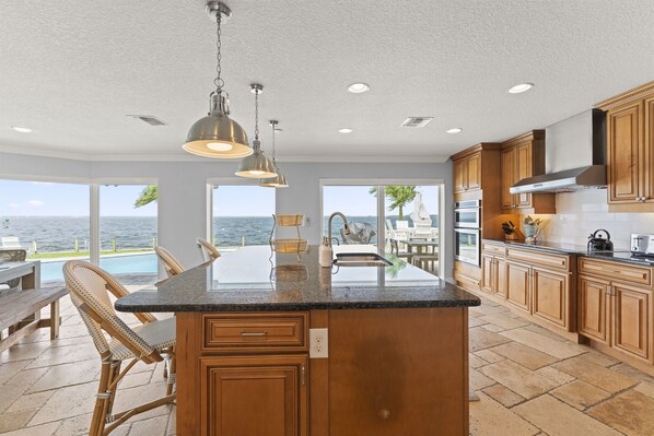 A kitchen with a large island, wooden cabinets, and a view of the ocean.