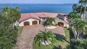 A coastal property with a red-tiled roof, a central driveway, and a view of the sea.