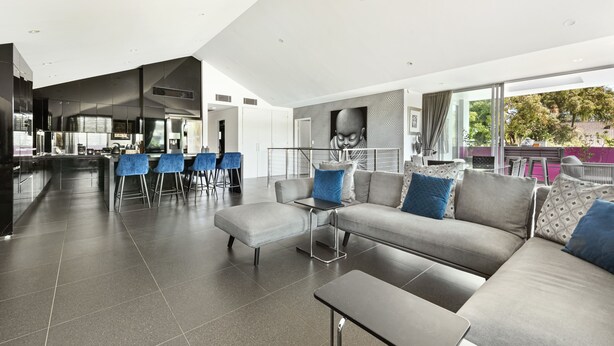 Un salon moderne avec un canapé gris, des fauteuils bleus et une petite table.