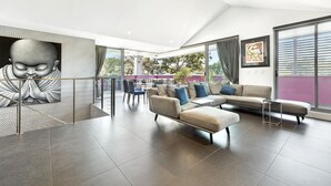 Un salon moderne avec un canapé d’angle, une table basse et une grande fenêtre donnant sur l’extérieur.