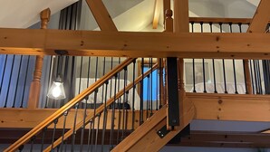 Un escalier en bois, une cheminée en briques et un luminaire au plafond.