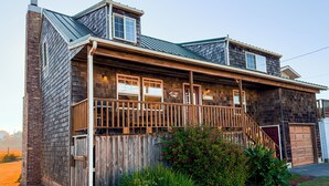Une maison en bois à deux étages, dotée d’un porche couvert, d’une cheminée en briques et d’un garage.