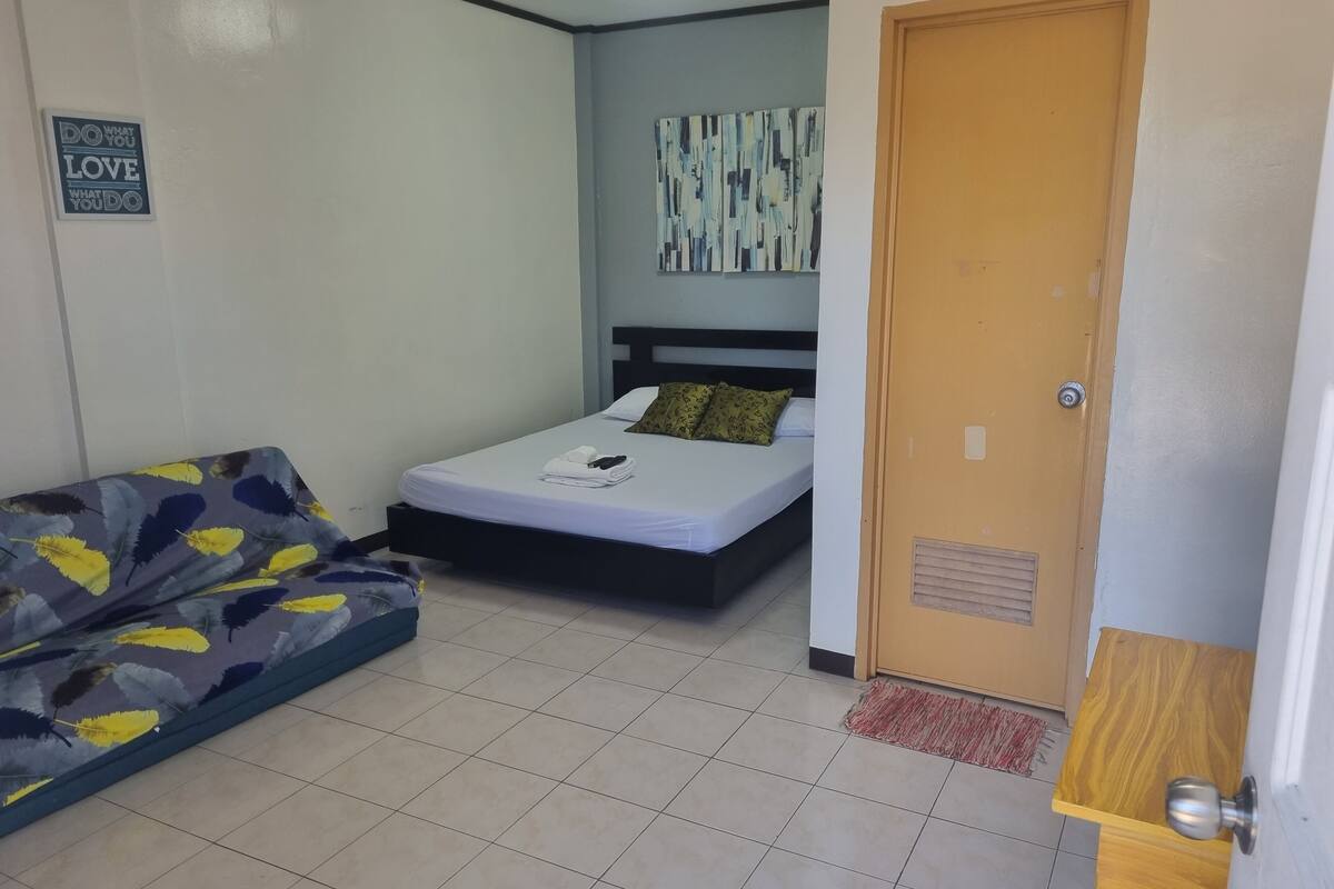 Un dormitorio con cama, sofá y una puerta.
