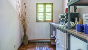 Eine kleine Küche mit Mikrowelle, Kaffeemaschine und einem kleinen Fenster.