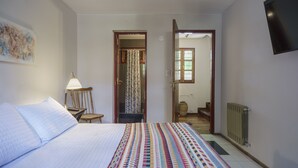 Ein Schlafzimmer mit einem Bett, einem Nachttisch, einer Lampe, einem Sessel und einem Fernseher.