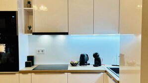 Una cucina moderna con mobili bianchi, un piano di lavoro in legno e un forno integrato.