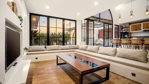 Ein modernes Wohnzimmer mit einem Ecksofa, einem Couchtisch aus Holz und einem Fernseher.