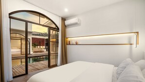 Ein modernes Hotelzimmer mit einem großen Bett, einer Glastür zum Poolbereich und einer eingebauten Klimaanlage.