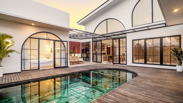Ein modernes Haus mit Schwimmbad, großen Fenstern und einer Holzterrasse.
