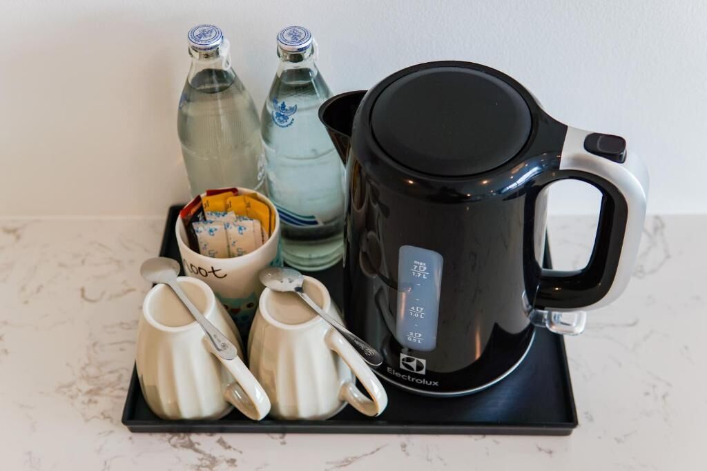 Une machine à café noire dotée d’un écran numérique, deux bouteilles d’eau et un plateau avec deux tasses blanches et une cuillère.