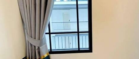 A room with a window, a curtain, and a blue bed.
