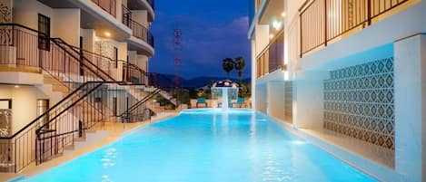 Una piscina con una fuente, rodeada de edificios de varios pisos con balcones y barandillas.