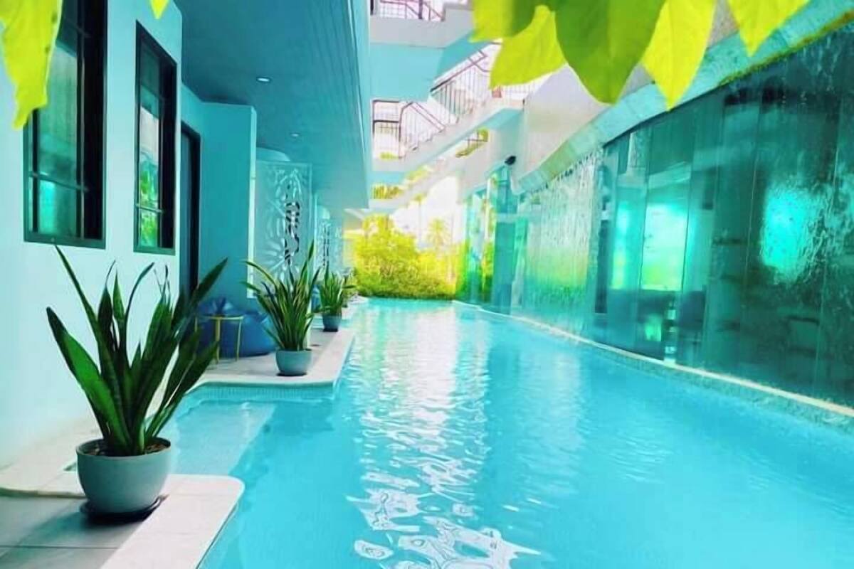 An indoor swimming pool with clear blue water, potted plants, and a modern architectural design.