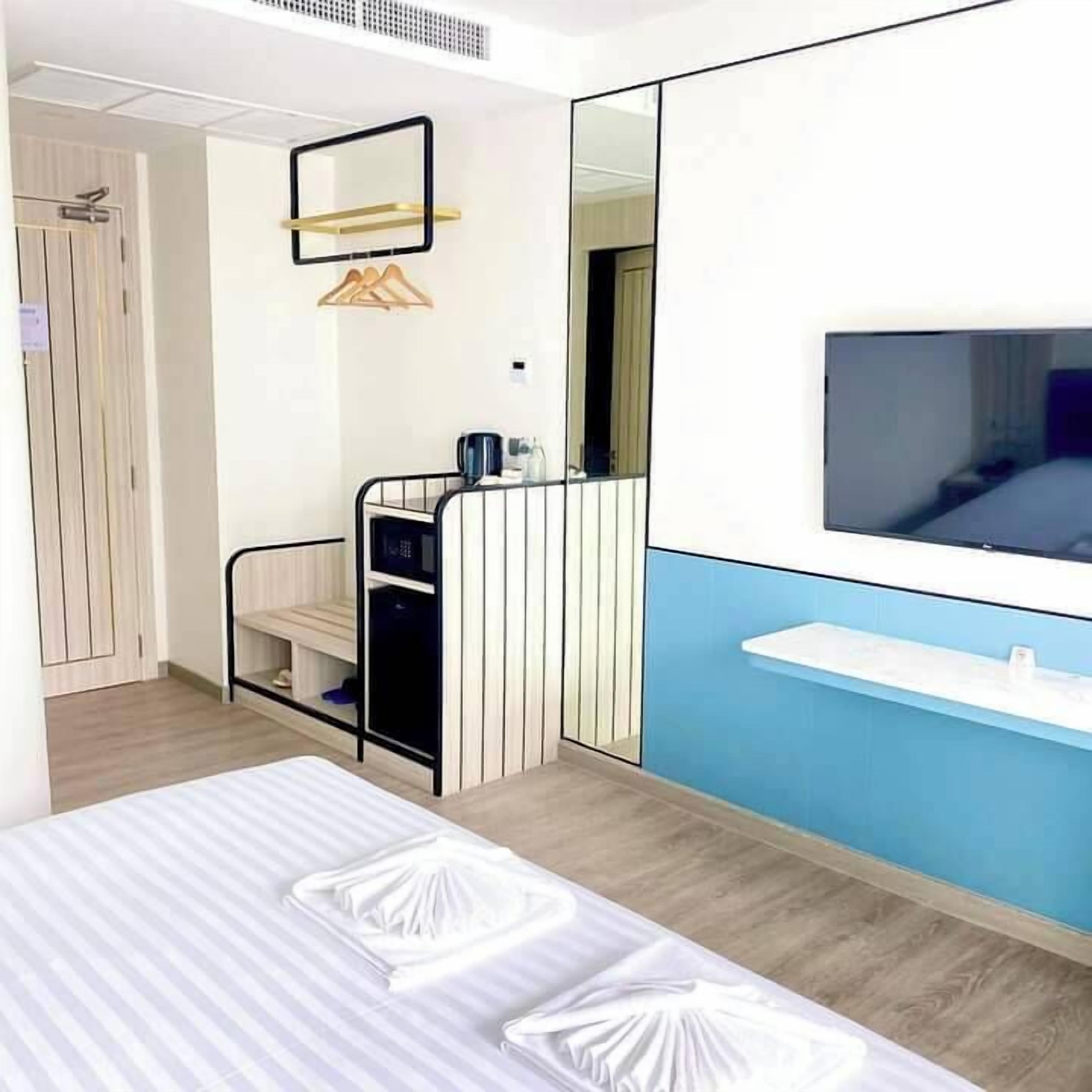 Een moderne hotelkamer met een bed, een televisie, een bureau met stoel en een kledingkast.