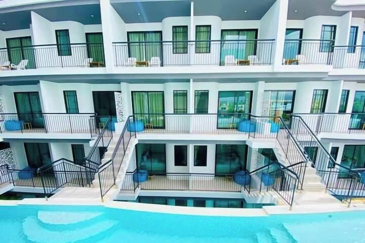 A multi-story hotel with balconies, a swimming pool, and a modern architectural design.