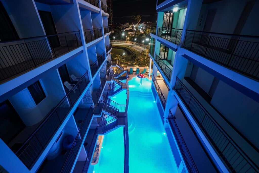 Ein mehrstöckiges Hotel mit einem zentral gelegenen Pool, Balkonen und Blick auf die Umgebung.