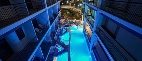 Ein mehrstöckiges Hotel mit einem zentral gelegenen Pool, Balkonen und Blick auf die Umgebung.