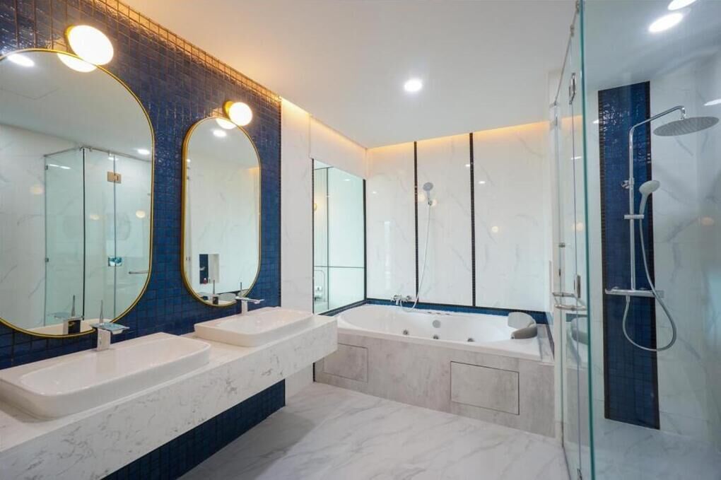 A modern bathroom with two sinks, a large bathtub, and a glass-enclosed shower area.