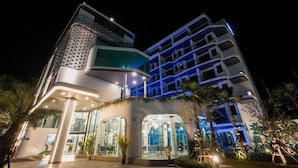 A modern hotel with a unique architectural design, featuring a curved facade and multiple balconies. - Poolrada Boutique Hotel (Thep Krasattri)