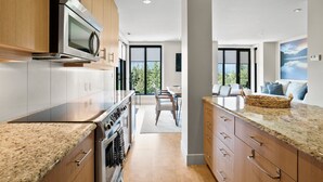 Een moderne keuken met granieten aanrechtbladen, roestvrijstalen apparatuur en een groot raam met uitzicht op de omgeving.