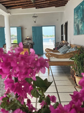 Una habitación con una cama de madera, vista al mar y un ventanal con contraventanas azules.