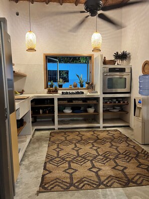 Una cocina compacta con horno integrado, dispensador de agua y ventana con vistas a zonas verdes.
