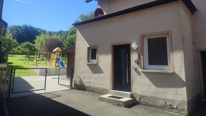 Un bâtiment à deux étages, à la façade beige, doté d’un toit recouvert de tuiles et d’un petit porche.