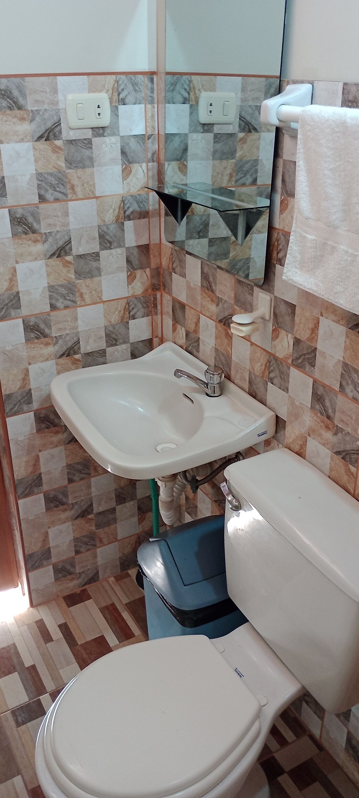 Une salle de bain avec un lavabo blanc, des toilettes et un miroir.