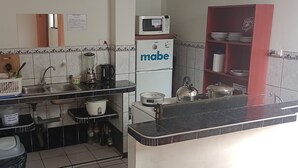 A kitchen with a sink, stove, microwave, and a water dispenser. - Travelers' House  (Huanchaco)