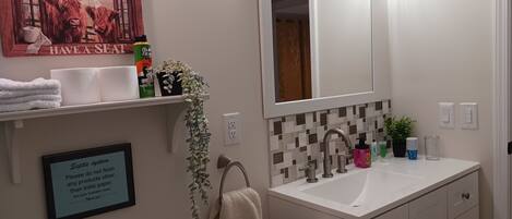 A bathroom with a sink, mirror, towel rack, and a sign about septic system.