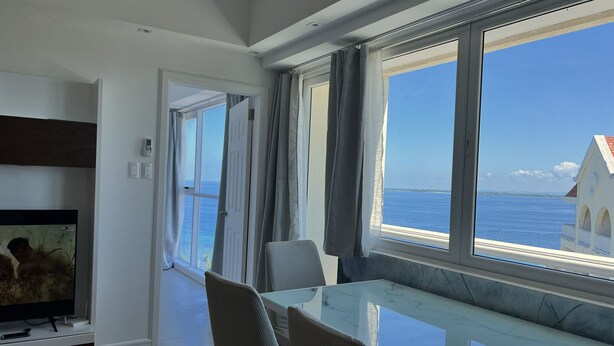 Un salon moderne avec une table en verre, un téléviseur à écran plat et une vue sur la mer.