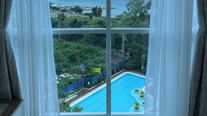 Une chambre dotée d’une grande fenêtre donnant sur une piscine et offrant une vue sur la mer.
